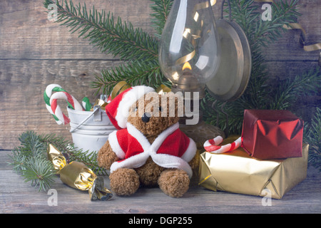 Vintage Christmas decoration with antique teddy bear in santa`s hat with burning vintage lamp over wooden background Stock Photo